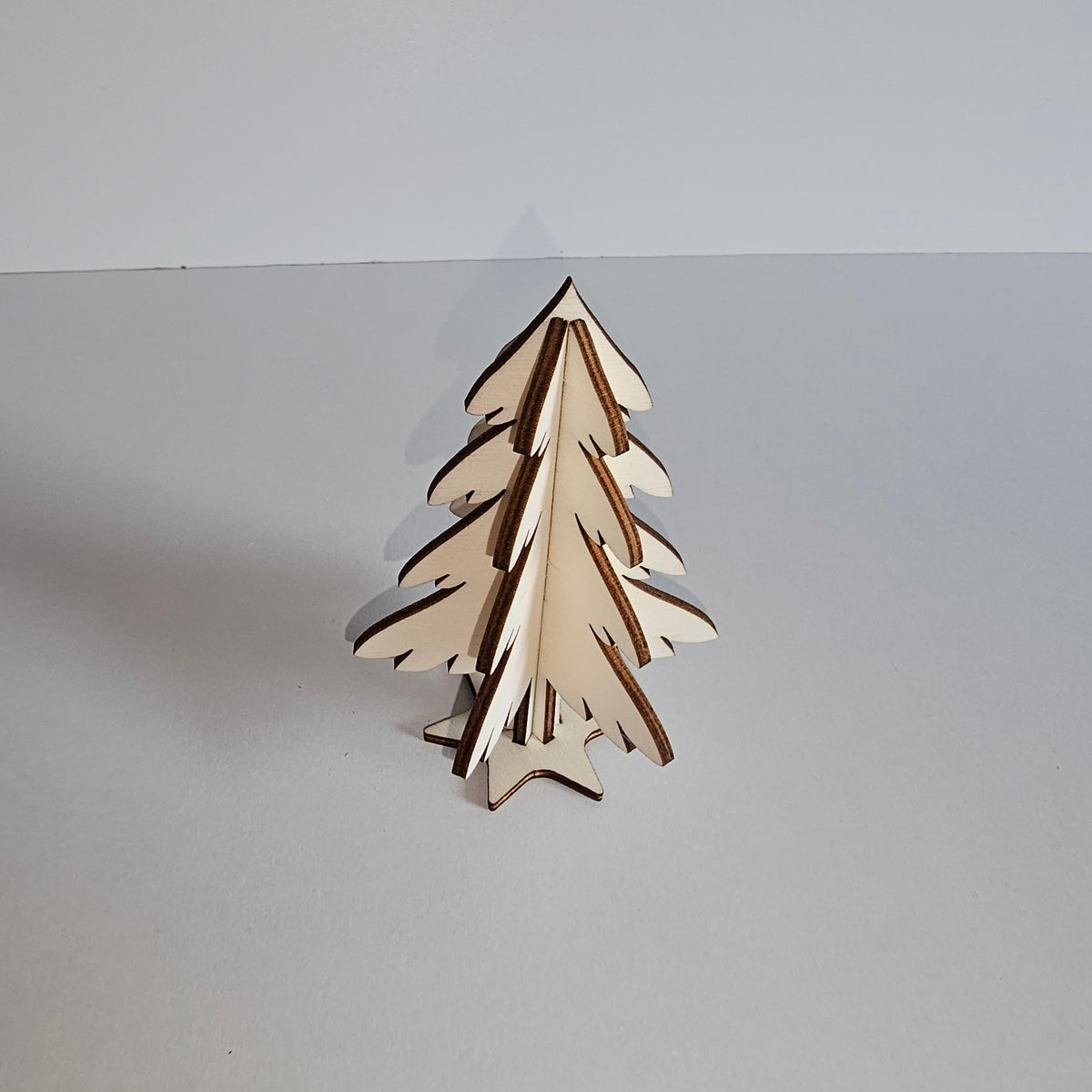 Schrägansicht des kleinen zusammengesteckten Holz-Tannenbaums auf Sternsockel